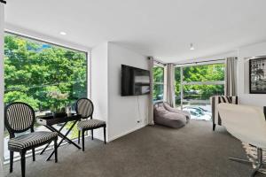 een woonkamer met een tafel, stoelen en een televisie bij Central Queenstown Luxury in Queenstown