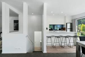 een keuken met witte muren en een aanrecht en krukken bij Central Queenstown Luxury in Queenstown +8 foto's