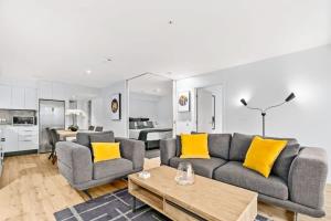 ein Wohnzimmer mit Sofa und gelben Kissen in der Unterkunft Cozy Coronet Peak Apartment at La Residence du Parc in Queenstown