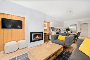 ein Wohnzimmer mit Couch und Kamin in der Unterkunft Cozy Coronet Peak Apartment at La Residence du Parc in Queenstown