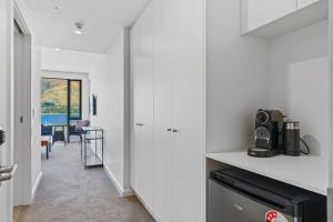 a kitchen with white walls and a table with a microwave at Lake View Studio Apartment in Wanaka