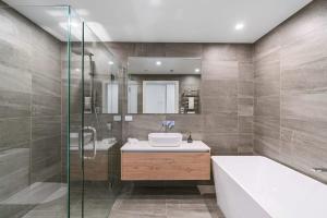 a bathroom with a tub and a sink and a shower at Lake View Studio Apartment in Wanaka
