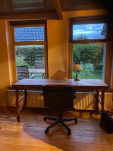 escritorio de madera en una habitación con 2 ventanas en Huis in Marrum uit 1880 met grote tuin., en Marrum