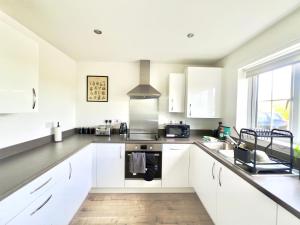 a kitchen with white cabinets and a stove top oven at BRAND NEW 3 BEDROOM HOUSE WITH GARDEN AND FREE PARKING in Wednesbury