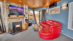 Una sala de estar con un sofá rojo y una chimenea. en Greenstone Heights, en Queenstown