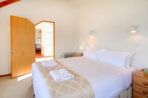 - une chambre avec un grand lit blanc et des serviettes dans l'établissement Ruby's Fernhill Vista, à Queenstown