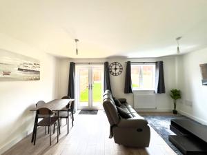 a living room with a couch and a table and a clock at BRAND NEW 3 BEDROOM HOUSE WITH GARDEN AND FREE PARKING in Wednesbury