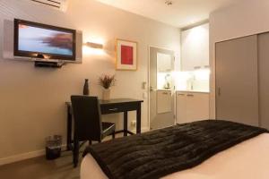 Schlafzimmer mit einem Bett und einem Schreibtisch mit einem TV an der Wand in der Unterkunft Luxury 1 Bedroom Studio in Queenstown