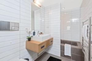 a white bathroom with a sink and a mirror at Luxury 1 Bedroom Studio in Queenstown