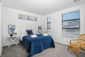 a bedroom with a bed with a blue blanket and a chair at Vacations on Riverslea in Wanaka