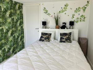 een wit bed in een slaapkamer met een groot raam bij Bel Acacia in De Haan