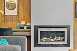 a living room with a fireplace with flames in it at Shotover Serenity in Queenstown