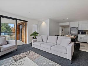 a living room with two white couches and a kitchen at Shotover Serenity in Queenstown