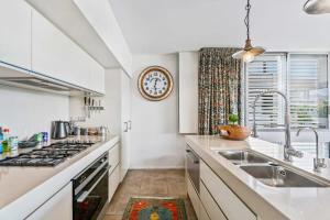a kitchen with a sink and a clock on the wall at Pembroke Luxury Apartment in Wanaka