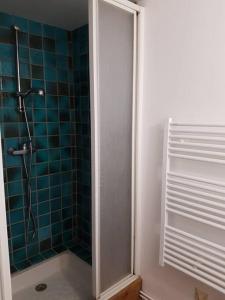 La salle de bains est pourvue d'une douche et d'un mur en carrelage bleu. dans l'établissement La maison du Rebours - Gîte à la campagne 6/8 pers, à Haussez