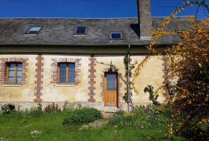 une ancienne maison en briques avec une porte et des fenêtres marron dans l'établissement La maison du Rebours - Gîte à la campagne 6/8 pers, à Haussez