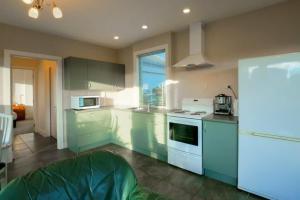 a kitchen with green cabinets and a stove top oven at Cosy on Kingston in Albert Town