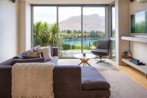 een woonkamer met een bank en een groot raam bij Stunning Lakeview 1 Bedroom Apartment in Queenstown