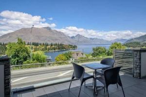 a table and chairs on a balcony with a view of a river at Luxury Lake View - 1 Bedroom in Queenstown