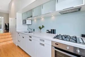 a kitchen with white cabinets and a stove top oven at Luxury Lake View - 1 Bedroom in Queenstown