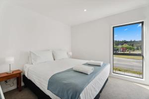 a white bedroom with a large bed with a window at Rivers Edge - Alberttown in Albert Town