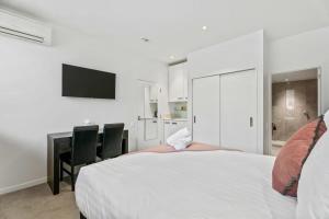 1 dormitorio con 1 cama, escritorio y TV en Tranquil Modern Studio, en Queenstown