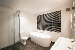 a bathroom with a tub and a toilet and a glass shower at Mataraki Magic in Wanaka +30 photos