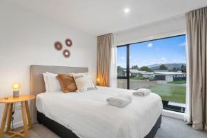 a bedroom with a large bed and a large window at Wanaka Riverside Townhouse Retreat in Albert Town