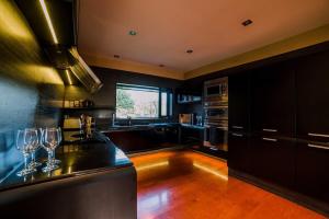 a kitchen with black cabinets and a counter with wine glasses at Entertainers Dream in Christchurch