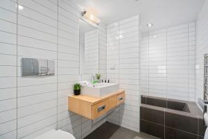 a white bathroom with a sink and a tub at Alpine Retreat Studio in Queenstown