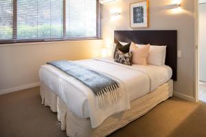 ein Schlafzimmer mit einem großen Bett mit weißer Bettwäsche und Kissen in der Unterkunft Alpine Retreat Studio in Queenstown