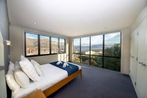 a bedroom with a bed with large windows at Mataraki Magic in Wanaka