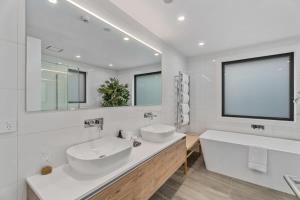 a white bathroom with two sinks and a large mirror at Lakeview Luxury Vista in Wanaka
