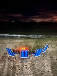 - deux chaises et une cheminée dans le sable sur la plage dans l'établissement Casa Pé na Areia SC, à Biguaçu