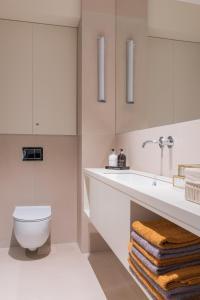 a white bathroom with a toilet and a sink at Natura Luxury Apartments II in Iława