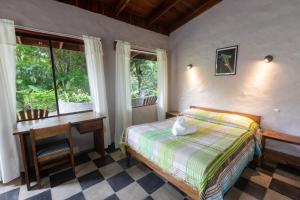 um quarto com uma cama, uma secretária e janelas em Elida Lodge Monteverde em Monteverde