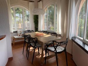 een eetkamer met een tafel, stoelen en ramen bij Villa Marta - Montgó in Denia