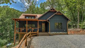 a small black house with a porch in the woods at Holiday House in Blue Ridge