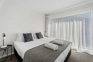 a white bedroom with a large bed and a large window at Alpine Adventurer's Abode in Albert Town