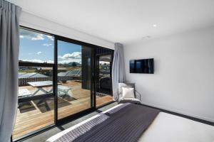 Schlafzimmer mit einem großen Fenster mit Blick auf eine Terrasse in der Unterkunft Views from the Heights in Wanaka