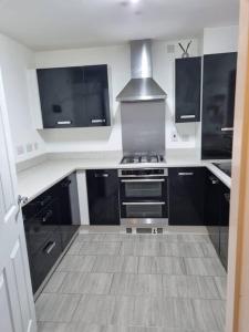 a kitchen with black cabinets and a stove at New Built Immaculate Condition in Rainham