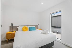 a white bedroom with a large bed and a window at Adventure Riverside Retreat in Albert Town
