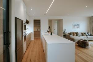 a kitchen with a white counter and a living room at Obelisk Dream with Spa in Wanaka