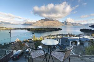 a table and chairs on a balcony overlooking a body of water at Modern 3 bedroom with stunning postcard views! in Queenstown