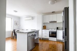 a white kitchen with white appliances and wooden floors at Sharp Road - Comfy & Cosy near Hospital and Cadia in Orange
