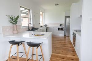 uma cozinha com um balcão branco e dois bancos em Haven on Hill, Beautifully renovated, Close to CBD em Orange