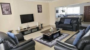 sala de estar con muebles de cuero y TV de pantalla plana en Artem Apartments - Apartment 2 en Kitwe