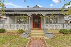 a white house with a red door and stairs at Kilarra House - Heritage Home on Byng St Sleeps 10 in Orange