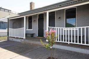 a house with a white porch and a plant at McNamara Lane - CBD, Firepit, 7 Smart TVs, Sleeps 11 in Orange