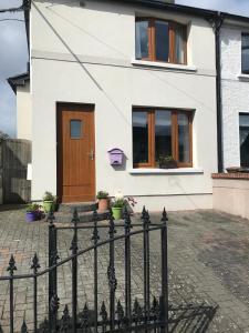 a white house with a wooden door and a fence at Spacious 3 bed townhouse in Dublin 12 in Dublin